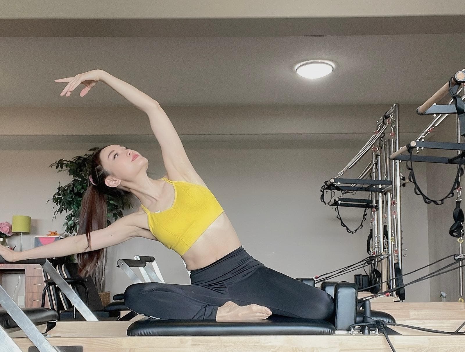 Professional Pilates instructor demonstrating advanced pose on reformer